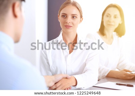 Business handshake by blonde woman and her partner at meeting. Concept of success and agreement