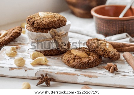 Homemade nutty vegan cinnamon cookies on white beige wooden board, close-up, natural light