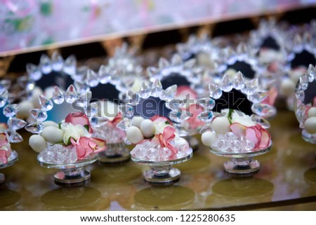 Elegant gifts made of mirror and candy for guests at a wedding or other celebration, decorated with flowers.