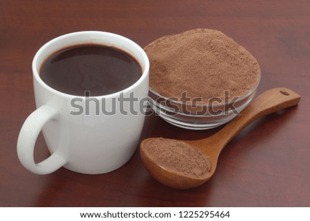 Mug with cocoa and cacao powder on wooden table