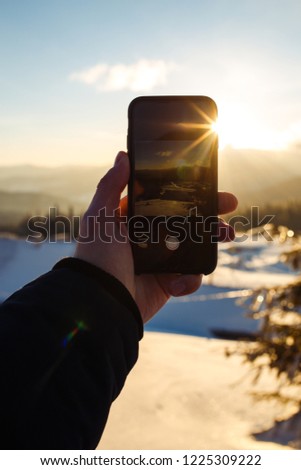 The guy takes on the phone a beautiful sunrise in the mountains. beautiful view of the mountains. Concept of travel, freedom, beauty of nature. beautiful day, sunny weather, blue sky.
