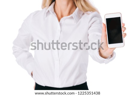 partial view of businesswoman showing smartphone with blank screen isolated on white