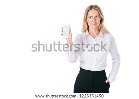 portrait of smiling businesswoman in eyeglasses showing smartphone with blank screen isolated on white