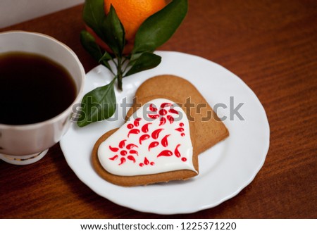 Red and white painted heart-shaped handmade gingerbread on a wooden table