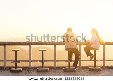 Lover feeling happy, drinking hot coffee during sitting and watching view of top of mountain. Enjoying nature sunrise  and relaxing in mountains.