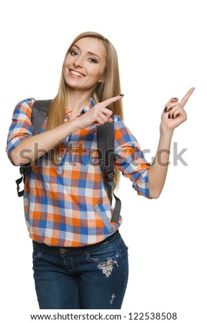 Young smiling female with backpack pointing to the side at blank space for your product or text, over white background.