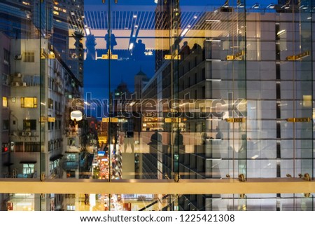 Hong Kong night street with buildings and  public transport. View from shopping mall window with people silhouettes reflections.  Royalty-Free Stock Photo #1225421308