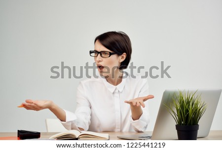 perturbed woman with glasses spreads her arms to the side in the office                               