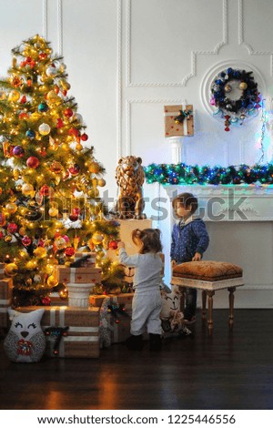 Children are waiting for a miracle in the New Year. Happy New Year! Merry Christmas! Christmas tree with christmas toys. Brother and sister dress up a Christmas tree.