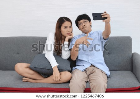 Attractive young Asian couple taking a photo or selfie together in living room. Love and romance people concept.