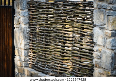 Decorative rustic village fence of wooden twigs. Natural tree trunk Texture. Garden decor.