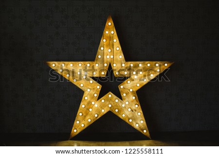 The wooden star with light. Under a black background.