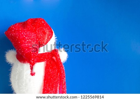 Christmas background in design of back of snowman model with a red hat and red scarf on blue background with copy space.