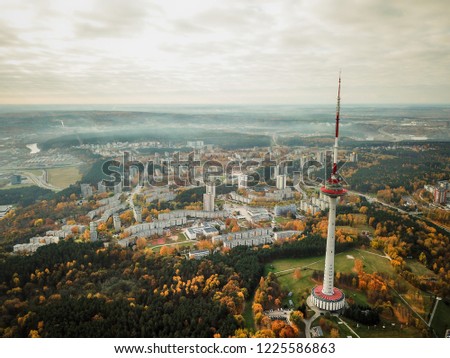 Aerial view of Vilnius TV tower with autumn colored panorama of the city, covered in light fog. 