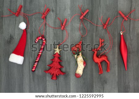 Christmas decorations and symbols of the festive season hanging on a red string line with pegs on rustic wood background. Christmas card for the festive season.
