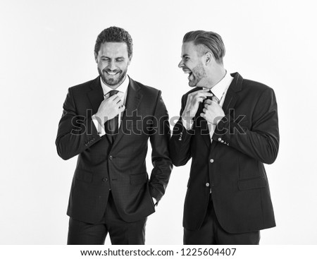 Stylish businessmen concept. Business partners correct ties by hands. Businessmen preparing outfit and moving ties. Businessmen with smiling faces wears classic suits, isolated on white background.