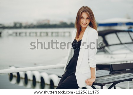 Stylish girl standing near river. Lady in a white whirt. Woman in a black pants.