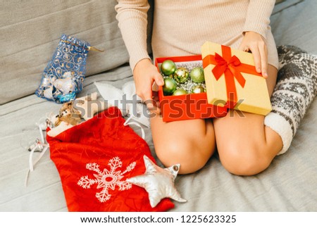 on the girl’s lap lies a box with Christmas toys and presents