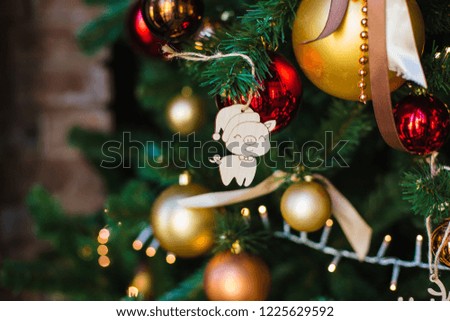 Christmas wooden toy in the form of a symbol of the approaching year-pig-hanging on a festive Christmas tree