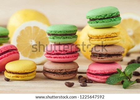 Green, pink, yellow and brown french macarons with lemon and coffee beans, soft focus background