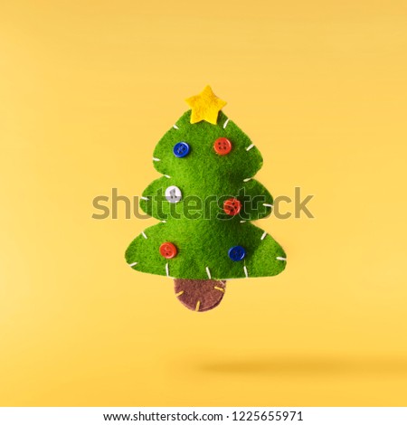 Christmas concept.  Creative Christmas conception made by falling in air green christmas cuddly tree over yellow background. Minimal concept