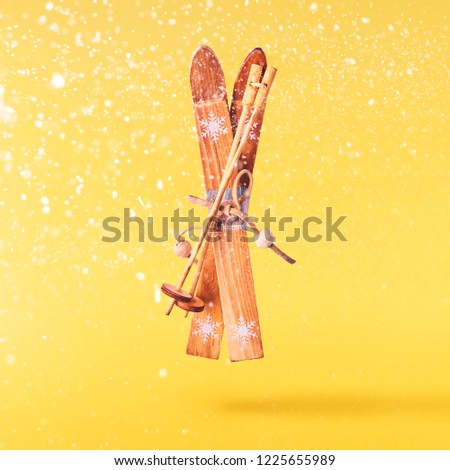Christmas concept.  Creative Christmas conception made by falling in air tiny ski toy over yellow background. Minimal concept