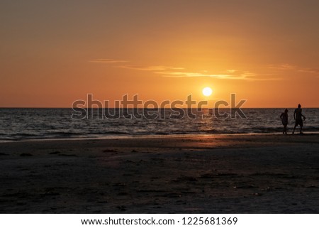 Couple takes romatic walk on Fort Myers Beach during sunseet on Estero Island in FL