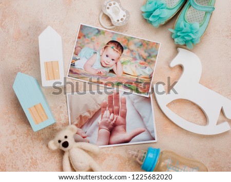 Baby girl pictures, accessories and toys on beige background. Top view, flat lay.