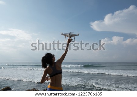 Woman photographer landing or taking off a drone on seaside 