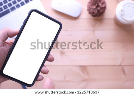 business man holding smartphone on office table desk background