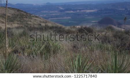 Dry hilltop view of mountains with cloudy blue sky.