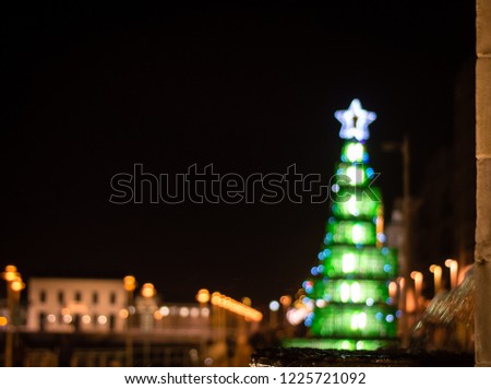 a unfocused christmas background with colorful lights on a Christmas tree, with the fountain of Pelayo on first term.Gijon, Spain, Europe