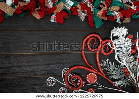 Festive Christmas red, green and white rag fabric garland over black wood background. Copy space included