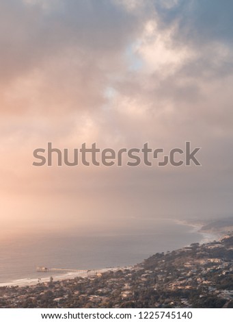 Vertical coastal view of La Jolla, San Diego, California, USA at sunset with Scripps Pier and a somewhat cloudy sunset. Buildings, palm trees and ocean. 