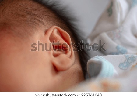 Ear of baby newborn with close-up macro picture during baby sleeping.