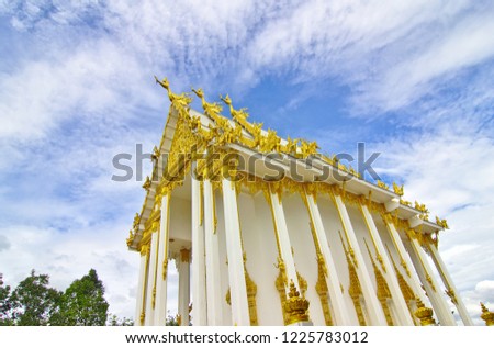 The temple is white with gold. Wat Bueng Ta Kat has white clouds with blue sky as the background. Located in Rayong province in Thailand.