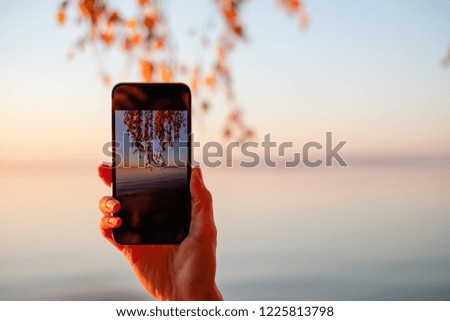 Travel blogger holding mobile device. Taking photo of a beautiful sunset on the smartphone with copy space