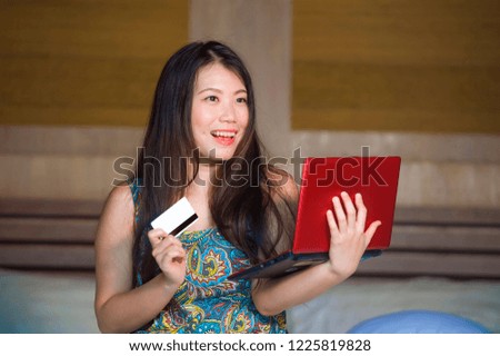 young beautiful and happy Asian Chinese woman using credit card internet banking on laptop computer at home in bed smiling excited shopping online buying in e-commerce and lifestyle concept