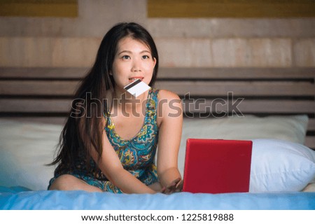 young beautiful and happy Asian Chinese girl using credit card internet banking on laptop computer at home in bed smiling excited shopping online buying in e-commerce and lifestyle concept