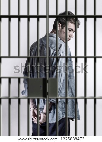 Young man in handcuffs in a jail