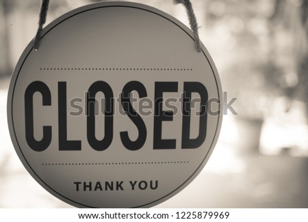 closed sign hanging on the glass door in black and white colors.
