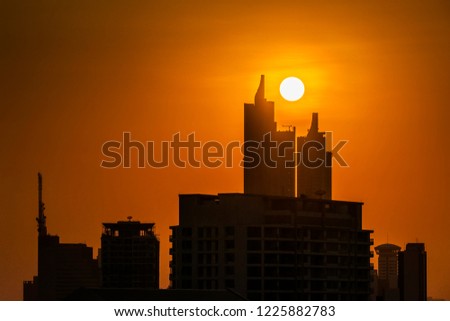Silhouette picture of sunset between two building at  on orange background.