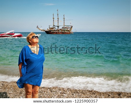 beautiful happy middle-aged woman sunbathes on Cleopatra beach in Turkey, Alanya. Tourist ship and blue sea and sky on background. concept of leisure and travel. Copy space or design. Toned picture