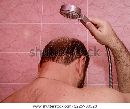 Man pours water on his head from the shower.