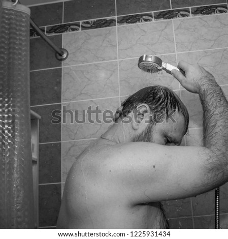 Black and white photo. The man gladly takes a shower.