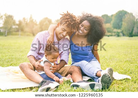 Happy black family having fun doing picnic outdoor - Parents and their daughter enjoying time together in a weekend day - Love tender moments and happiness concept - Focus father and mother on faces