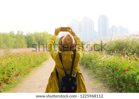 Traveler taking picture at beautiful park with flower to the building with nice light in the morning .