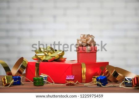 Red gift boxes with ribbons and colorfull ornaments on blurred background, concept  for Christmas greeting celebration. Copy space on right.