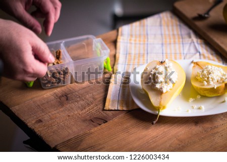 Backstage with a shot of a pear with cottage cheese, nuts, cinnamon and honey on a wooden, subject table. The hands of the photographer in the frame. Creating a photo