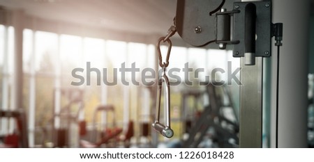 Close-up of a new pull rope handle in a blurred empty gym. Vertical weight lifting element, vertical traction. Modern gym interior with equipment.